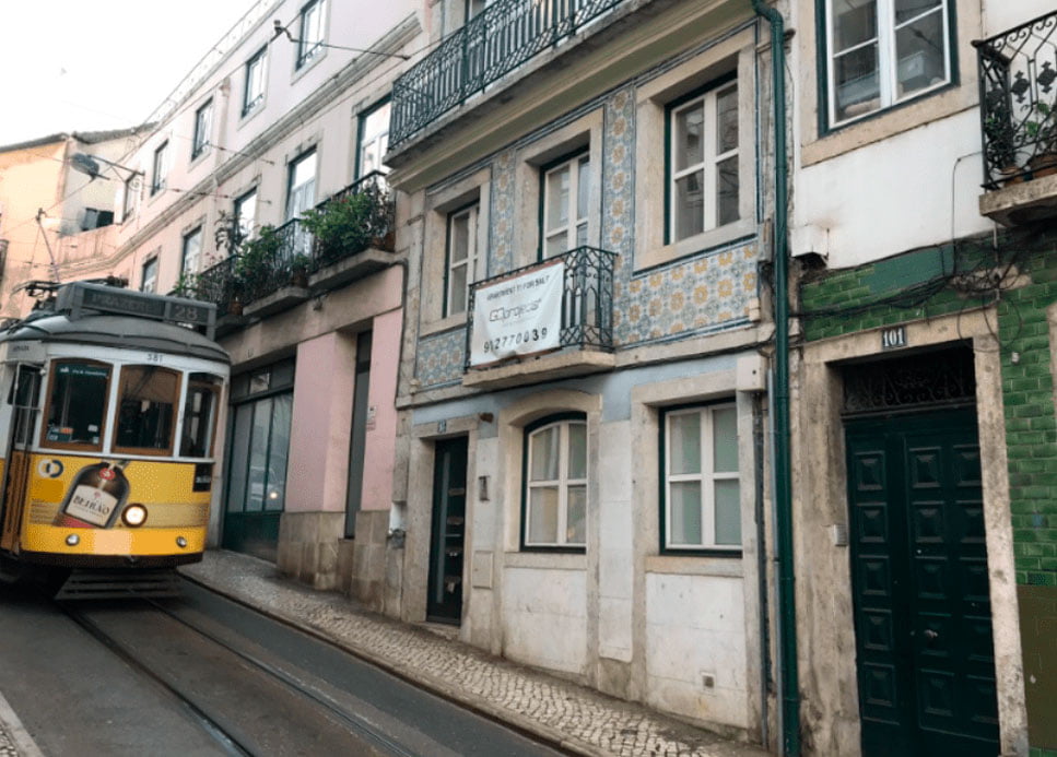 Buildings seen from the streets of Lisbon, Portugal, with a yellow tram in circulation.