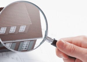 Graphic of a hand holding up a magnifying glass in front of a house
