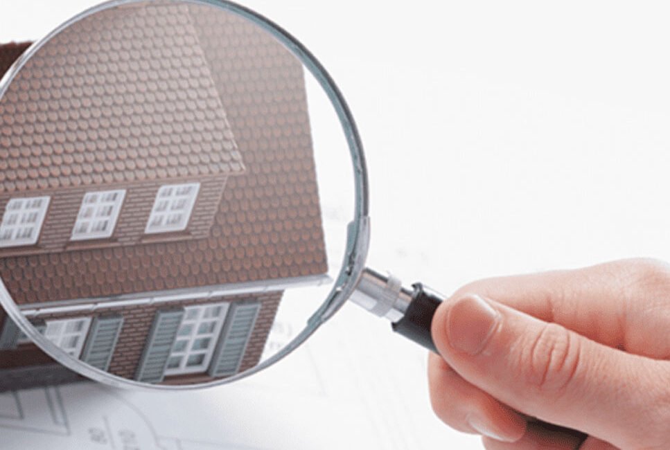 Graphic of a hand holding up a magnifying glass in front of a house