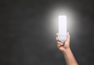 Light bulb held in front of a dark canvas.