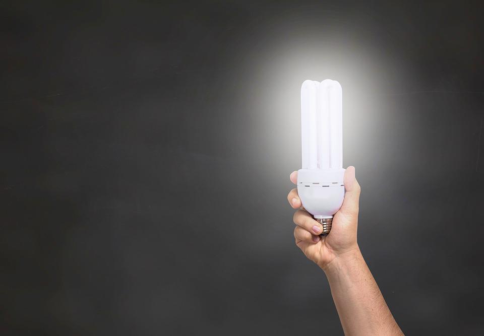 Light bulb held in front of a dark canvas.